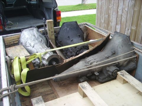 1978 Ford Bronco - Multiple transmission assemblies are being transported in the bed of a pickup truck, secured with wooden bracing and straps.