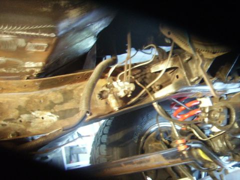 1978 Ford Bronco - The undercarriage of a vehicle is shown, revealing suspension components, brake lines, and a tire.
