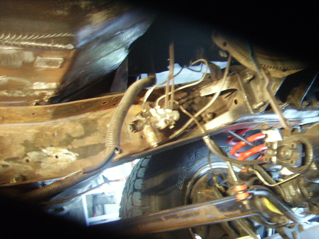 Underbody view of vehicle suspension with brake lines and a tire visible