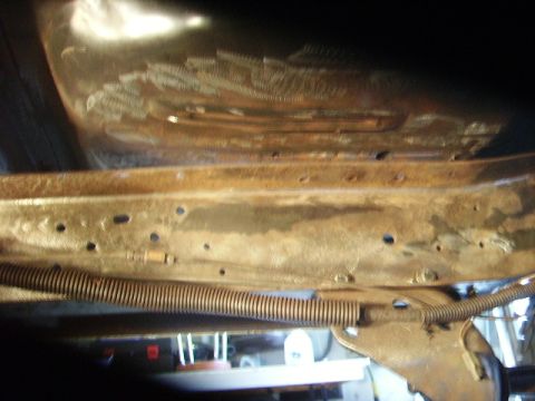 1978 Ford Bronco - Undercarriage view of a heavily rusted vehicle frame, with visible spring and wiring.