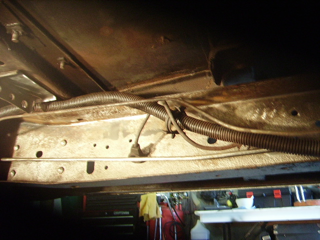 Underside of a vehicle frame with wiring and conduit visible