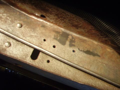 1978 Ford Bronco - Detail of a corroded metal section with visible rivets and drilled holes.