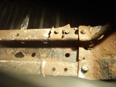 1978 Ford Bronco - Close-up of heavily corroded vehicle frame components with visible bolts and mounting points.