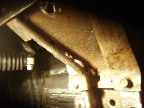 1978 Ford Bronco - Close-up view of a heavily rusted metal bracket, likely from the undercarriage of a vehicle.