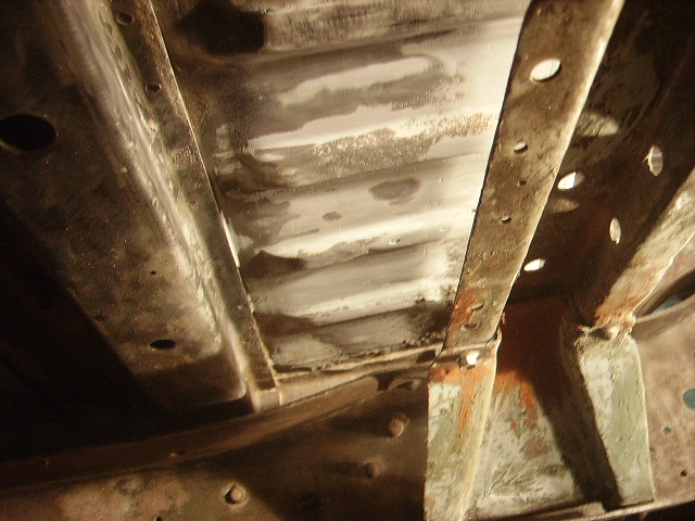 Underside of vehicle frame with structural beams and crossmembers.