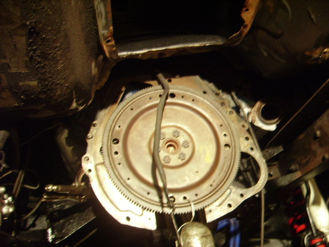 Vehicle flywheel with gear teeth, viewed from below.