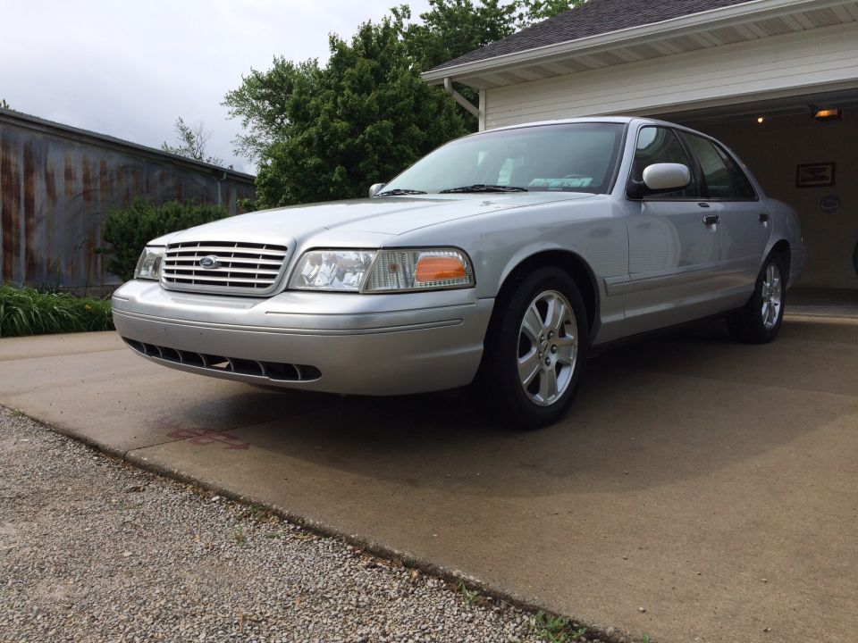 Silver 2003 Ford Crown Victoria LX Sport parked in front of a garage.