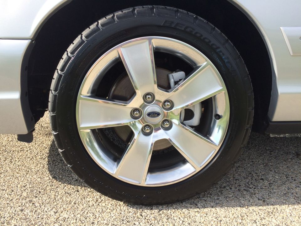 Close-up of a silver 5-spoke Ford wheel with a BFGoodrich tire. The Ford logo is visible on the center cap