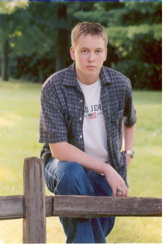1998 Mercury Sable - A young man poses for a photo while leaning on a rustic wooden fence in a grassy, tree-filled area.