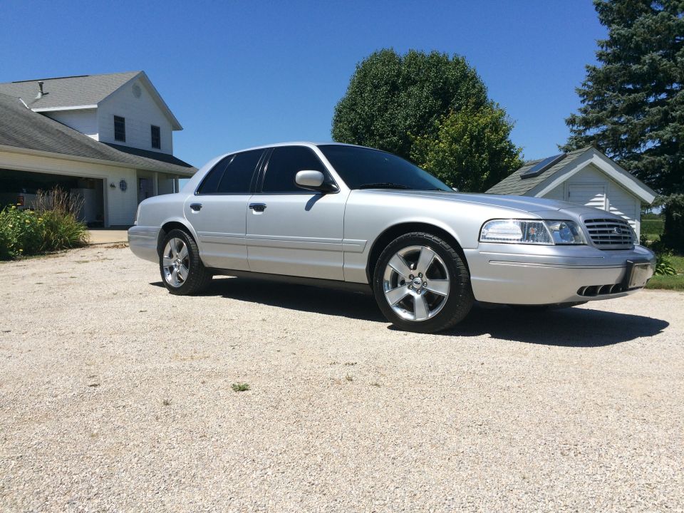 Silver Ford Crown Victoria parked in a driveway with a house in the background