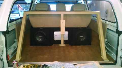 1979 Ford Bronco - The rear interior of a white SUV, likely a Ford Bronco, is customized with two large subwoofers and an amplifier mounted between the rear s…