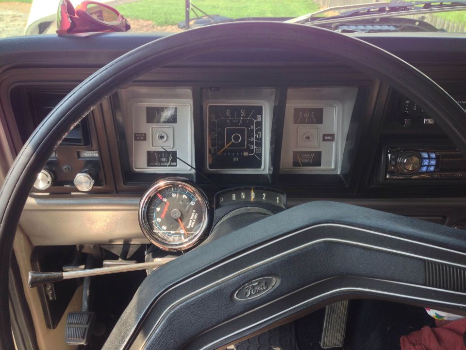 Close-up of a vintage Ford dashboard with a steering wheel, tachometer, and instrument cluster.