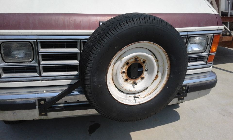 Front view of a vintage van with a spare tire mounted on the bumper.