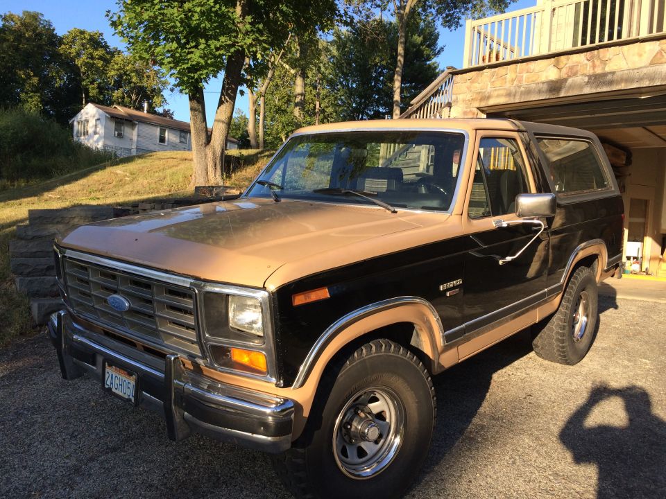 1983 Ford Bronco, tan and black, parked in driveway.