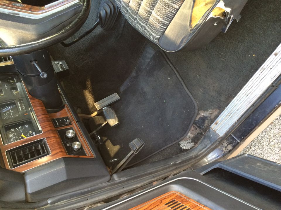 Interior of a classic vehicle showing steering wheel, dashboard, and pedals.