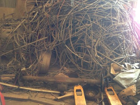 1979 Ford Bronco - A large, tangled pile of wires and cables is shown, with a rusty vehicle axle assembly visible in the foreground. Two yellow hydraulic jack…