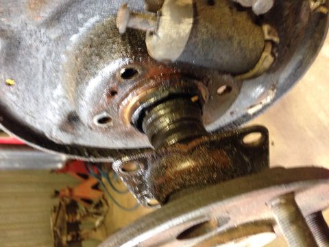 1979 Ford Bronco - A close-up, angled view shows a heavily greased and rusted brake drum assembly with visible bolts and a spindle protruding from the center.…