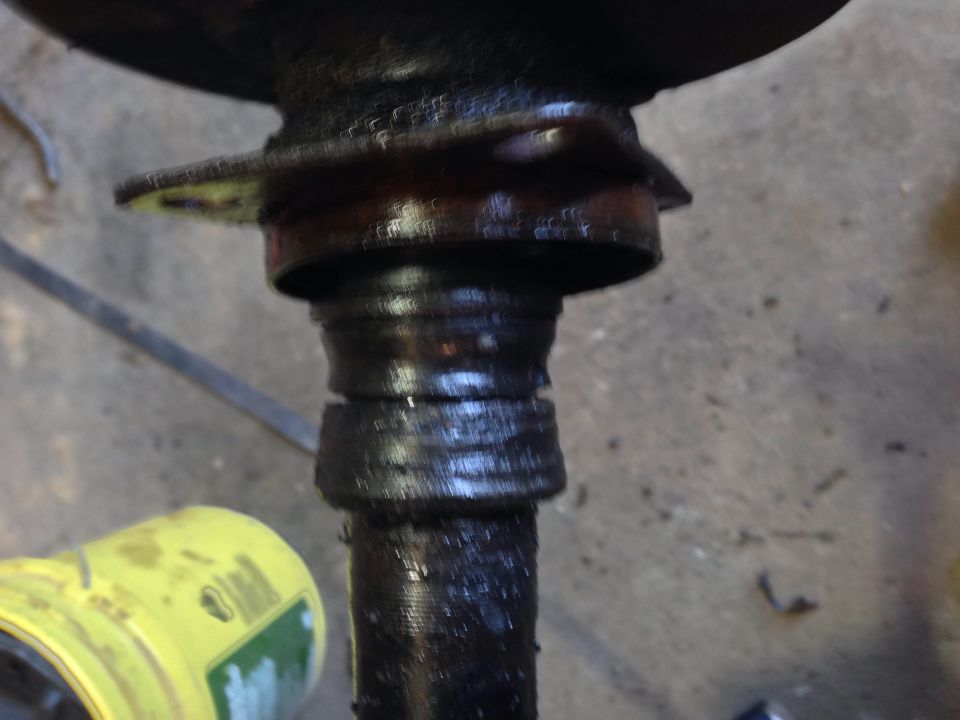 Greased metal shaft with grooves, yellow container in foreground.