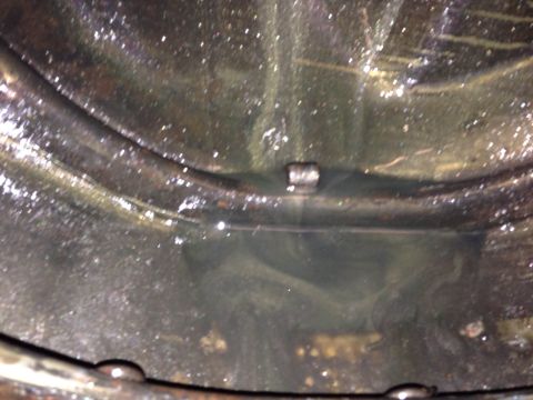 1979 Ford Bronco - A close-up view inside a dark, wet, and dirty cylindrical tank or reservoir. A metal rod or pipe runs horizontally across the middle, with…