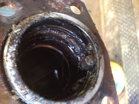 1979 Ford Bronco - A close-up view of a heavily soiled and rusted metal part, likely a component from a vehicle's engine or drivetrain, showing internal threa…