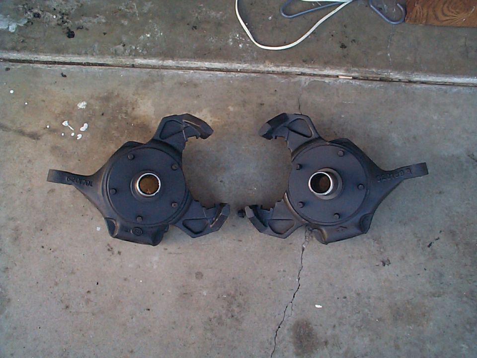 Pair of cast steering knuckles or spindles laid on a concrete garage floor