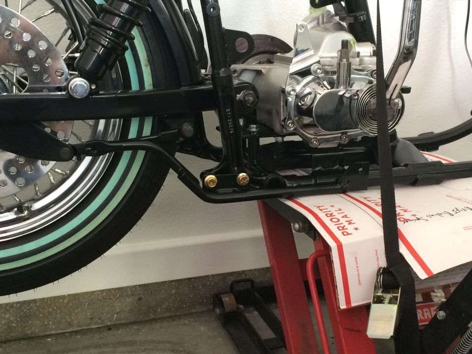 Motorcycle rear wheel, shock, engine, and frame on a red lift.