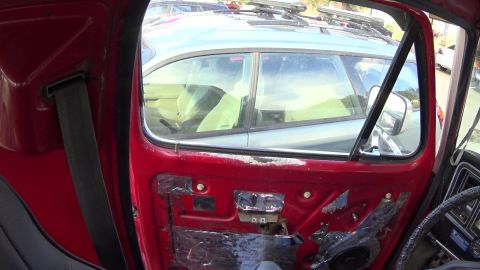 1978 Ford Bronco - Interior view of a red vehicle door with sound deadening material applied. The window shows the interior of another vehicle with light-colo…