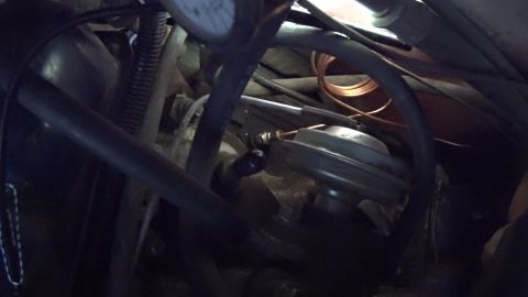 1978 Ford Bronco - This is a close-up view of a vehicle's engine bay, focusing on various hoses, a diaphragm actuator, and a small copper coil. The lighting i…
