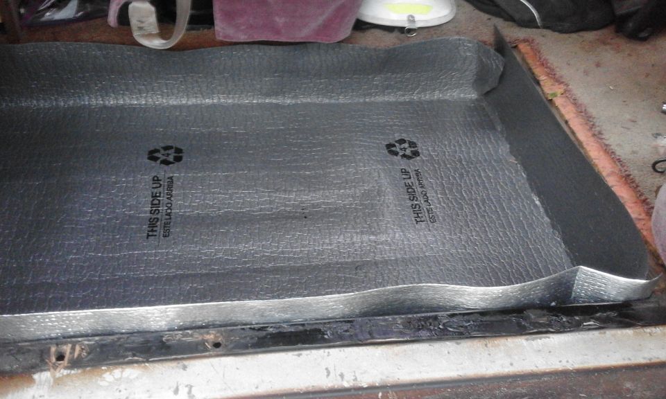 Silver reflective insulation with text "THIS SIDE UP" installed in a vehicle.