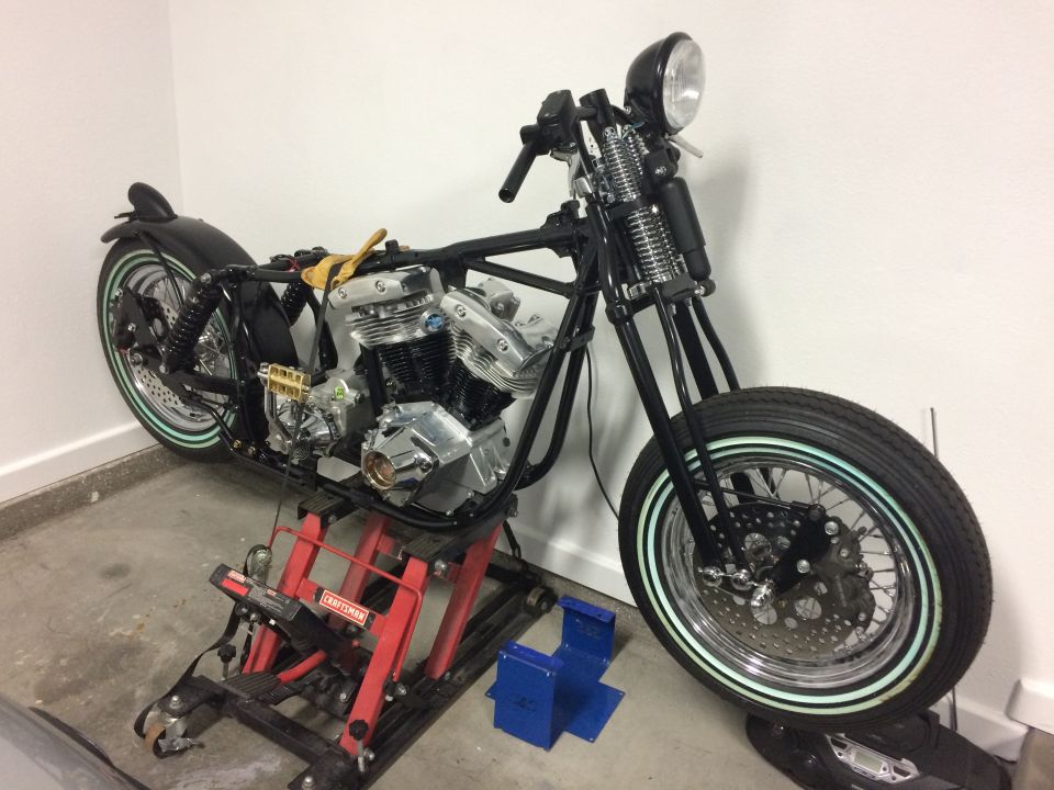 Custom motorcycle on a red hydraulic lift in a garage.