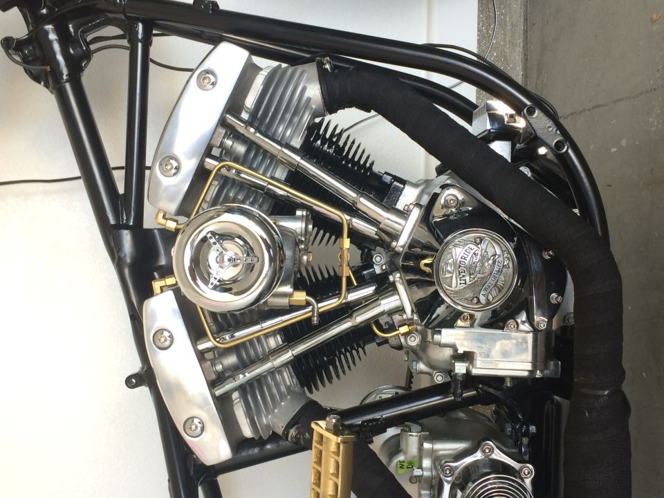 Custom motorcycle V-twin engine with chrome, brass, and black exhaust wrap.
