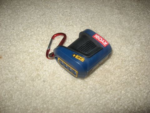1994 Ford Bronco - A blue and yellow Ryobi ONE+ battery pack with a red carabiner attached is lying on a cream-colored carpet.