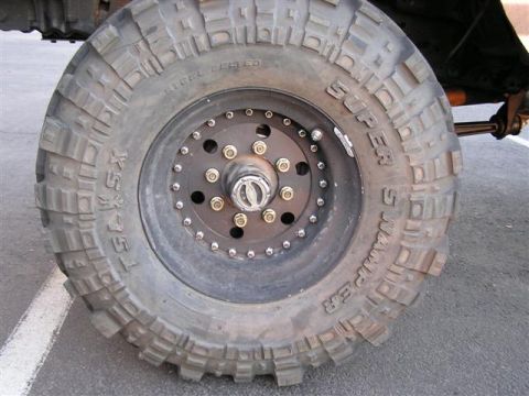 1994 Ford Bronco - A Super Swamper tire with aggressive tread is mounted on a black beadlock wheel, showing off-road capability.
