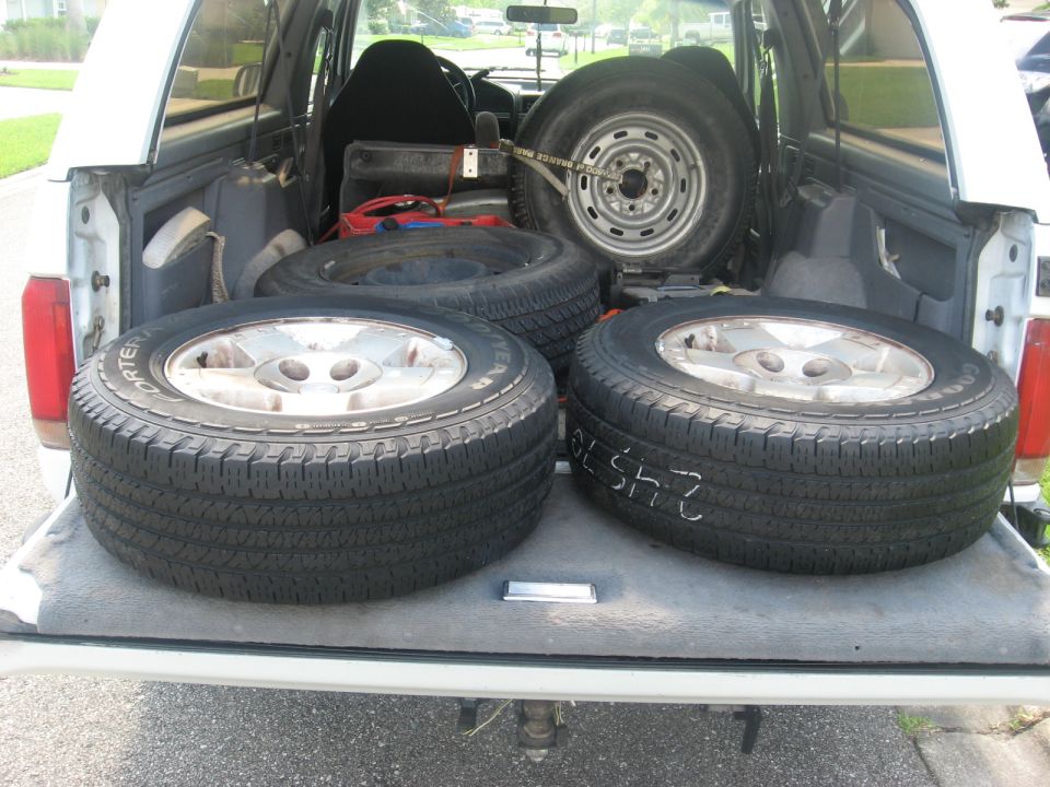 White Ford Bronco bed with four tires loaded.