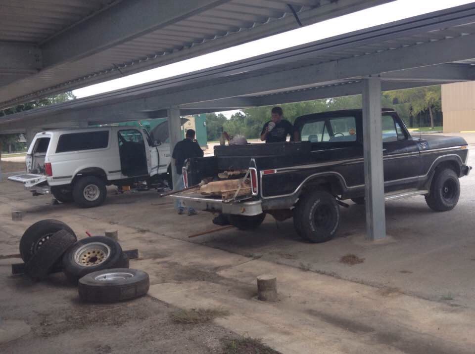 White SUV and black pickup truck under a cover, with tires in the foreground.