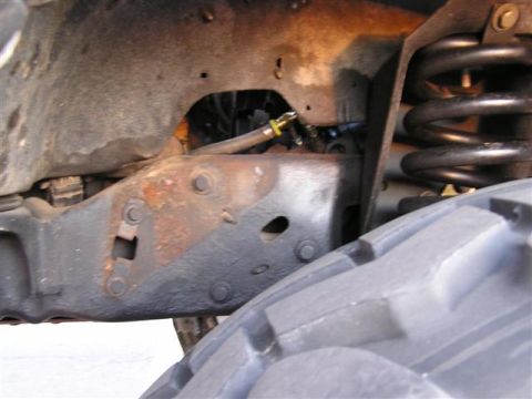 1994 Ford Bronco - Undercarriage view shows a rusty frame, suspension spring, and part of a tire.