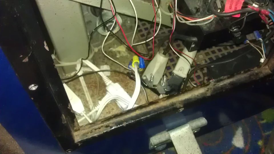 Close-up of internal wiring, connectors, and electrical boxes inside a machine.