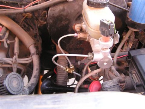 1994 Ford Bronco - Close-up of a vehicle's brake master cylinder assembly with various hoses and electrical connectors.