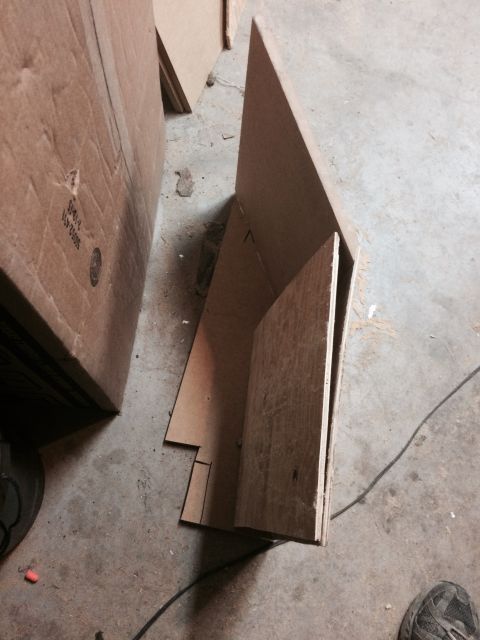 1979 Ford Bronco - Cardboard and wood pieces are arranged on a concrete floor, possibly in a workshop or garage setting. A black cord runs across the floor.