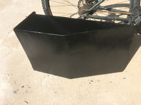 1979 Ford Bronco - A black, angular cargo box is mounted behind the rear wheel of a bicycle. The box appears to be made of metal and is painted a glossy black.