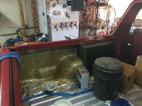1979 Ford Bronco - The bed of a red pickup truck is being modified with a fiberglass enclosure and sound deadening material. Various tools and supplies are vi…