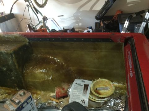 1979 Ford Bronco - The interior of a red vehicle, likely a truck bed or SUV cargo area, is being lined with fiberglass. Various materials and tools, including…
