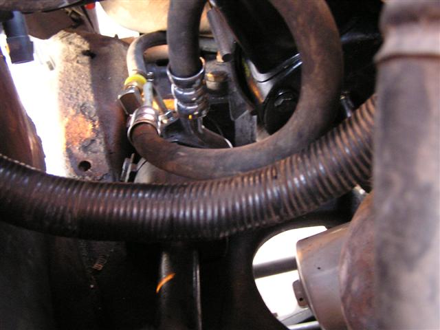 Close-up of engine hoses and metal components, with a Supermotors logo at the bottom right