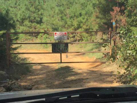 1993 Ford Bronco - A rusty metal gate blocks a dirt road leading into a wooded area. The gate has two signs, one reading "PRIVATE PROPERTY AUTHORIZED PERSONNE…