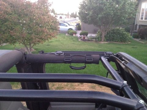 2005 Jeep Wrangler - The interior of a Jeep Wrangler is shown, focusing on the roll cage and padded grab handles above the doors. The vehicle is parked in a gra…