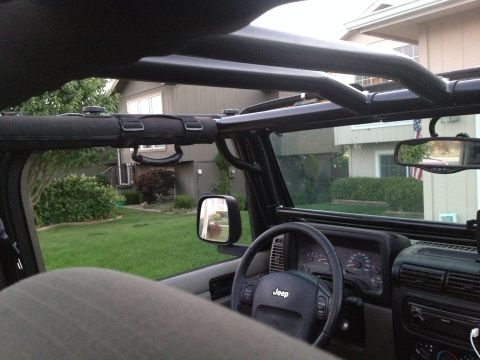 2005 Jeep Wrangler - Interior view of a Jeep Wrangler, showing the steering wheel, dashboard gauges, and a roll cage. The exterior view through the windshield r…