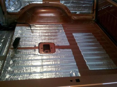 1982 Ford Bronco - Sound deadening material being installed on the floor of a vehicle's interior.