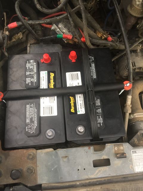 1993 Ford Bronco - Dual Duralast batteries are installed in the engine bay, secured by black straps and red caps.