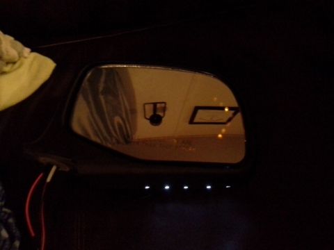 1993 Ford Bronco - Close-up of a car's interior mirror, showing a camera and illuminated indicator lights below.