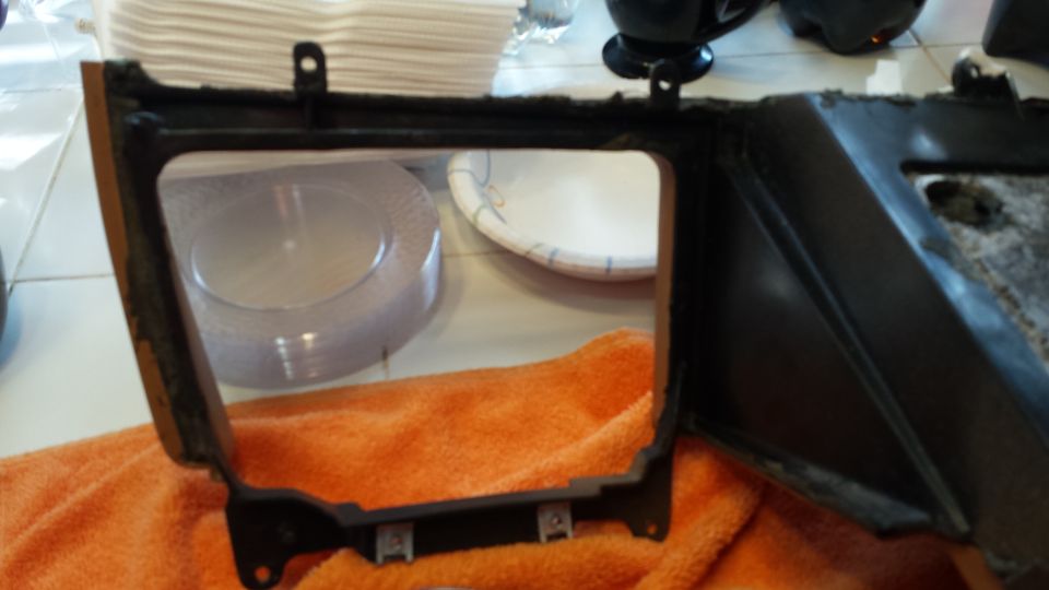 Black plastic car interior trim piece with rectangular cutout on orange towel.
